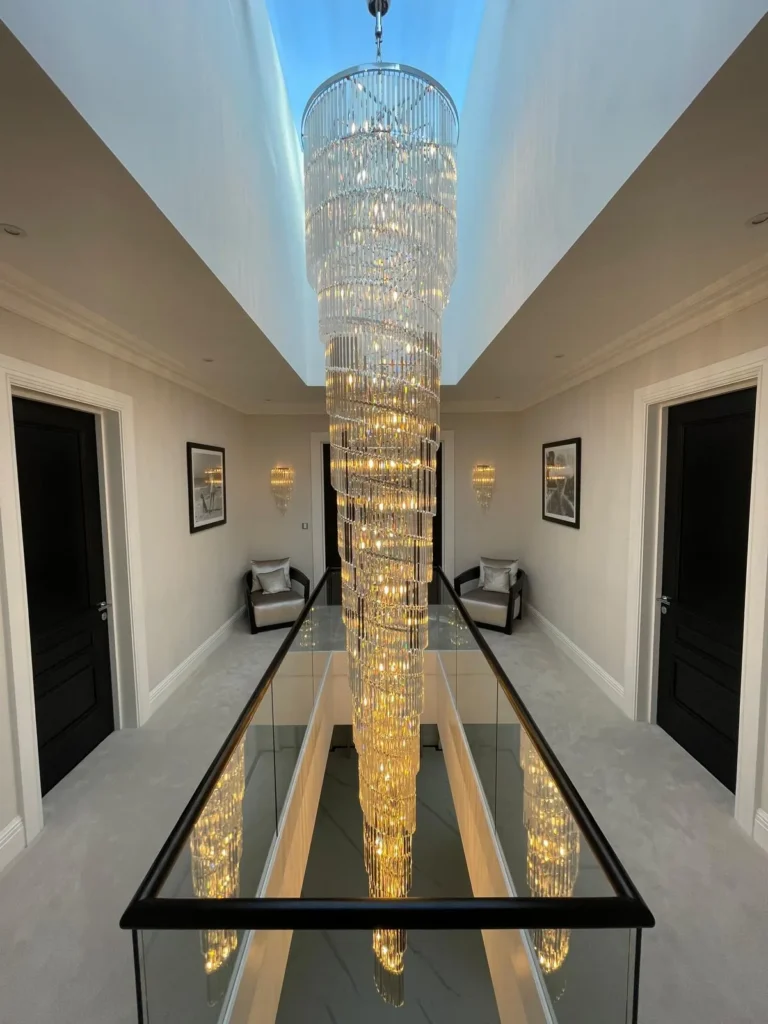 Long cascading chandelier suspended over a glass-sided stairwell