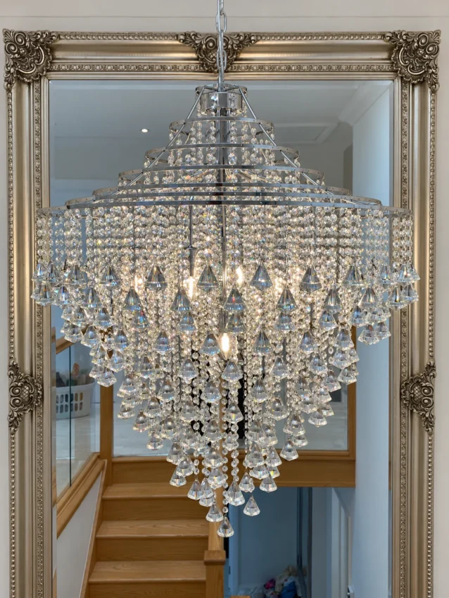 Crystal chandelier with hanging drops in front of an ornate mirror